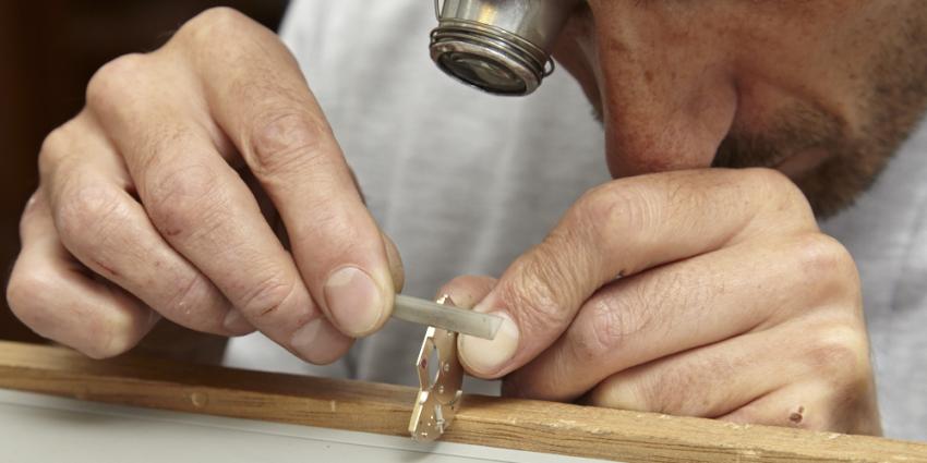 A watchmaker finishing a bridge at Garrick's workshop