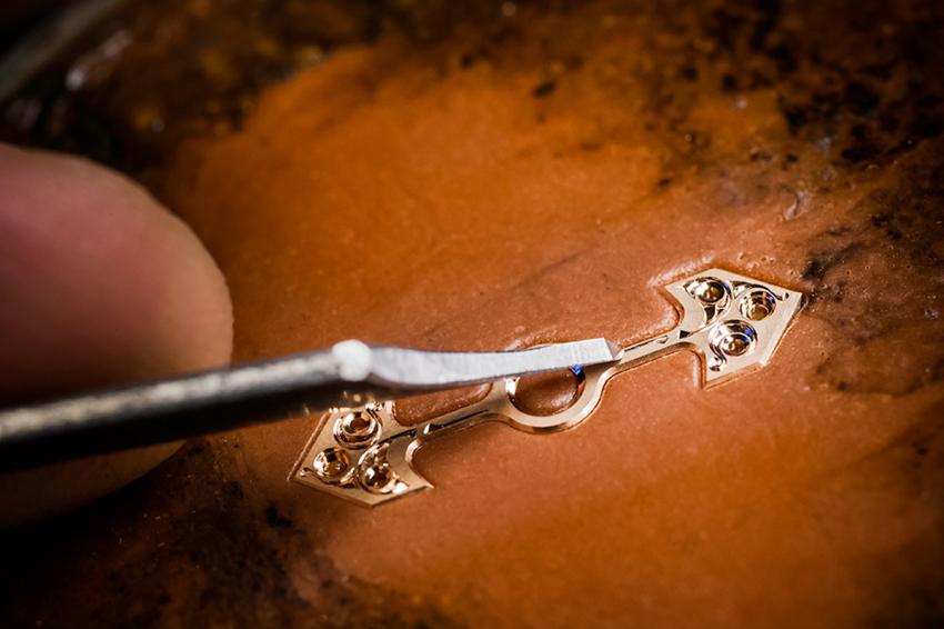 engraving the gold bridge of the tourbillon of the Girard-Perregaux Cat’s Eye Tourbillon.