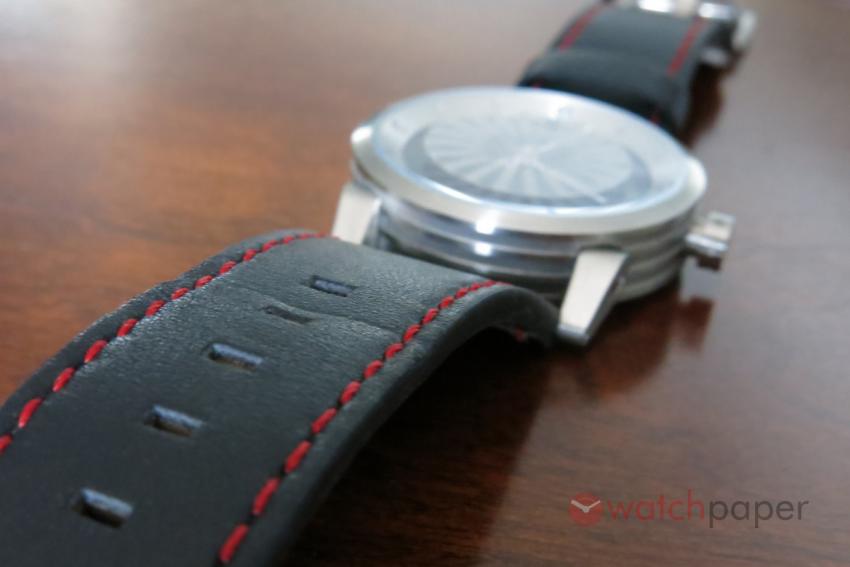 The black leather strap has red stitching and rectangular holes.
